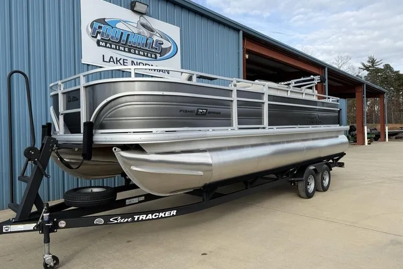 Slide: The Image of 2026 Sun Tracker Fishin' Barge 22 DLX pontoon boat on trailer at marine center. - 3