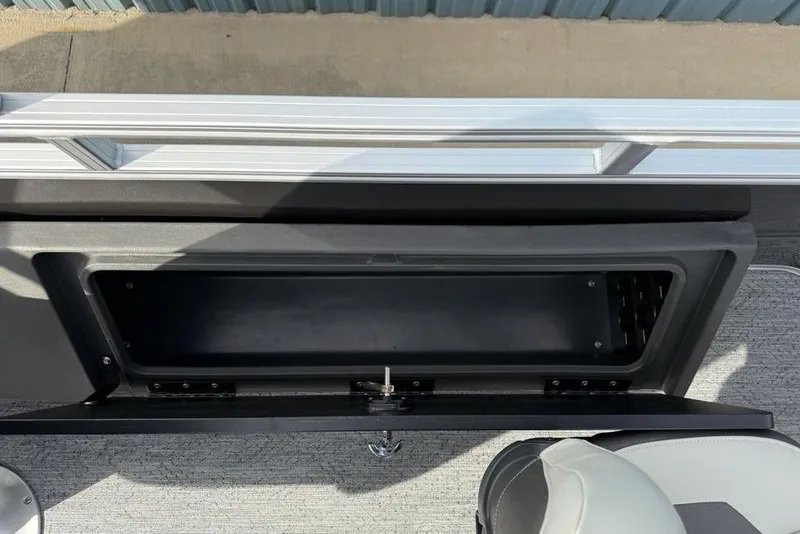 Slide: The Image of 2026 Sun Tracker Fishin' Barge 22 DLX storage compartment with open lid, showcasing interior space. - 30