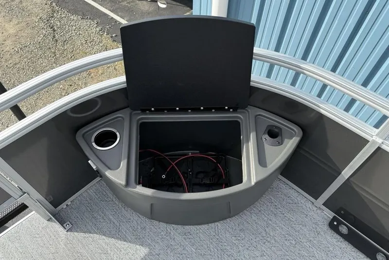 Slide: The Image of 2026 Sun Tracker Fishin' Barge 22 DLX storage compartment with cup holders and wiring. - 9
