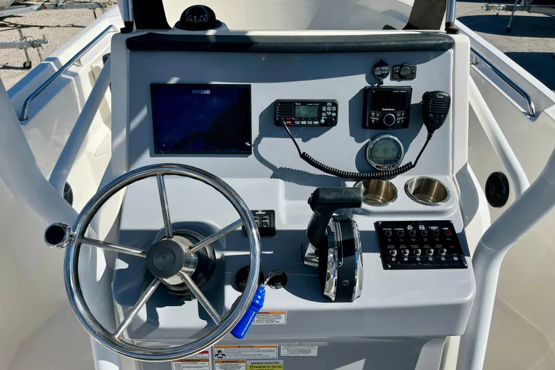 Slide: The Image of 2023 Trophy T24CC boat dashboard with steering wheel, controls, and navigation equipment. - 19