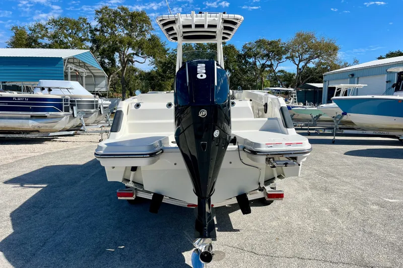 Slide: The Image of 2023 Trophy T24CC boat with outboard motor, parked in a marina under clear blue skies. - 7