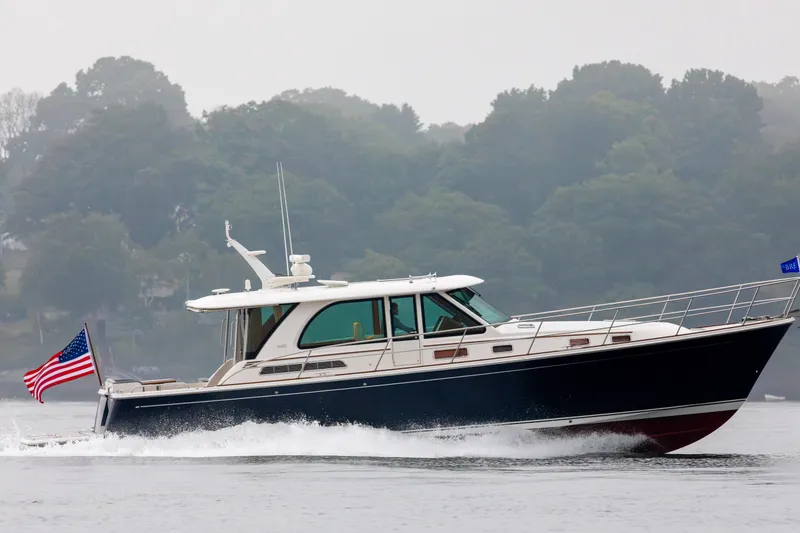 Slide: The Image of 2027 Sabre 45 Salon Express yacht cruising on a misty lake with American flag. - 2