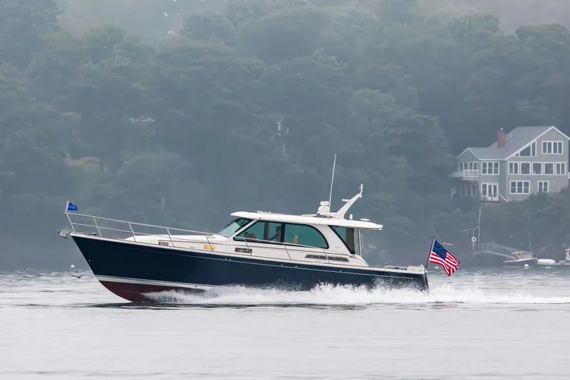 Slide: The Image of 2027 Sabre 45 Salon Express cruising on a misty lake near shoreline homes. - 4