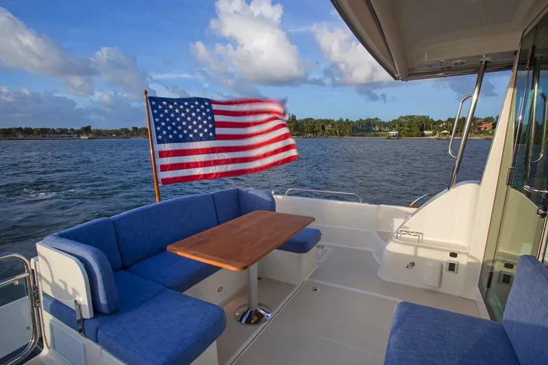 Slide: The Image of Manufacturer Provided Image: Sabre 45 Salon Express 2026 yacht with American flag, blue seating, and wooden table on deck. - 6