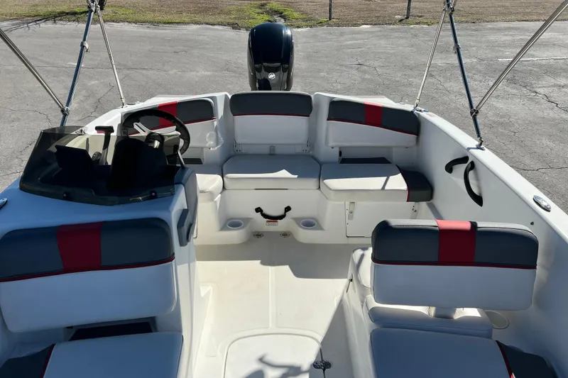 Slide: The Image of 2022 Tahoe T18 boat interior with seating and steering wheel, parked on pavement. - 12