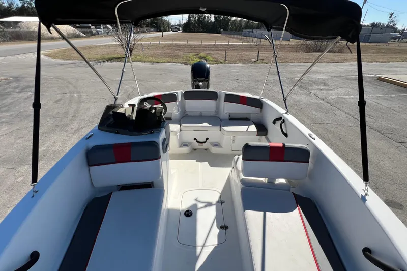Slide: The Image of 2022 Tahoe T18 boat interior with seating and canopy, parked on pavement. - 13