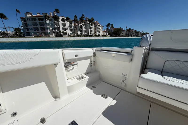 Slide: The Image of 2021 Pursuit S 378 Sport boat interior with luxury seating, near waterfront buildings. - 17