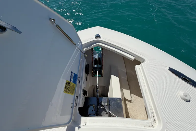 Slide: The Image of 2021 Pursuit S 378 Sport boat anchor compartment with open hatch, on clear blue water. - 29