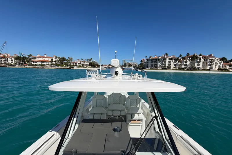 Slide: The Image of 2021 Pursuit S 378 Sport boat cruising near waterfront buildings under clear blue sky. - 31