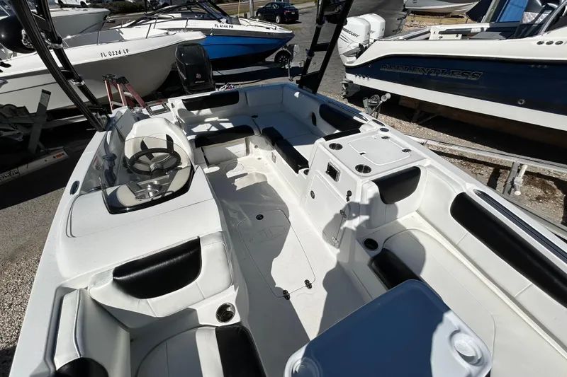 Slide: The Image of 2017 Tahoe 2150 boat interior with seating and steering wheel, docked among other boats. - 11