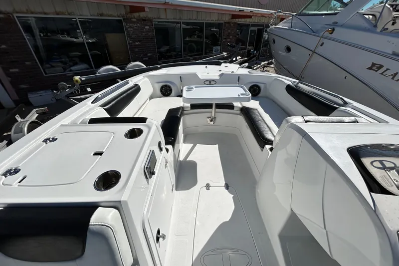 Slide: The Image of 2017 Tahoe 2150 boat interior with seating and table, docked near other boats. - 12