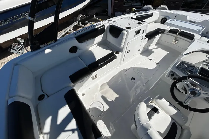 Slide: The Image of 2017 Tahoe 2150 boat interior with seating and steering wheel, docked beside another boat. - 13