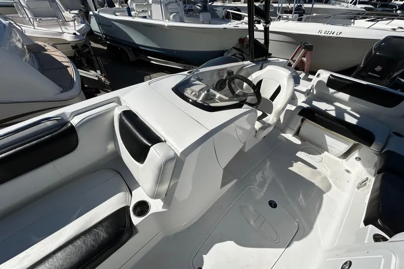 Slide: The Image of 2017 Tahoe 2150 boat interior with steering wheel and seating, docked among other boats. - 7