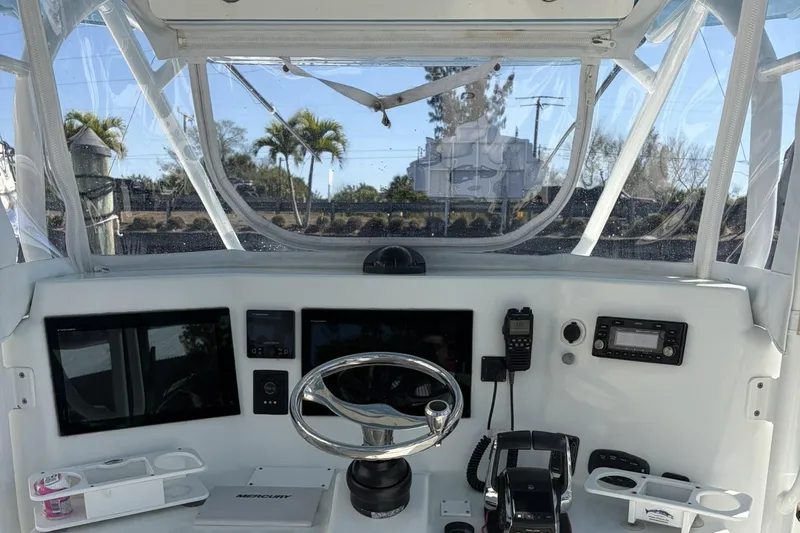 Slide: The Image of 2009 Yellowfin 42 Offshore boat helm with steering wheel, electronics, and clear canopy. - 9