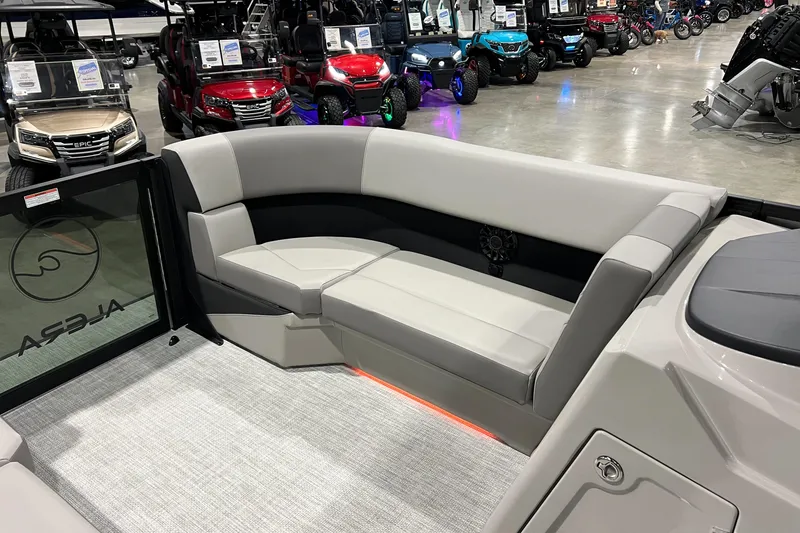 Slide: The Image of Luxurious seating on 2026 Alera A22Q boat, showcased indoors with golf carts in background. - 6
