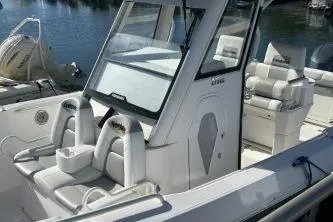 Slide: The Image of 2013 Everglades 275 Center Console boat with white seating and helm, docked by the water. - 2