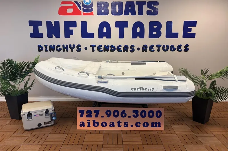 The Image of Inflatable Caribe L-9 boat display with contact information and decorative plants. - 12