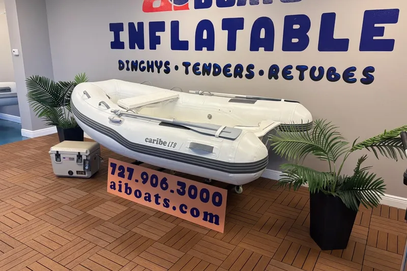 Slide: The Image of Inflatable Caribe L-9 boat displayed indoors with contact information and decorative plants. - 14