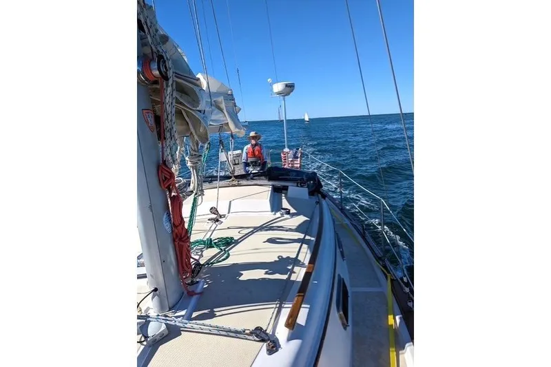Slide: The Image of 1988 Island Packet 27 sailboat cruising on open water under clear blue skies. - 2