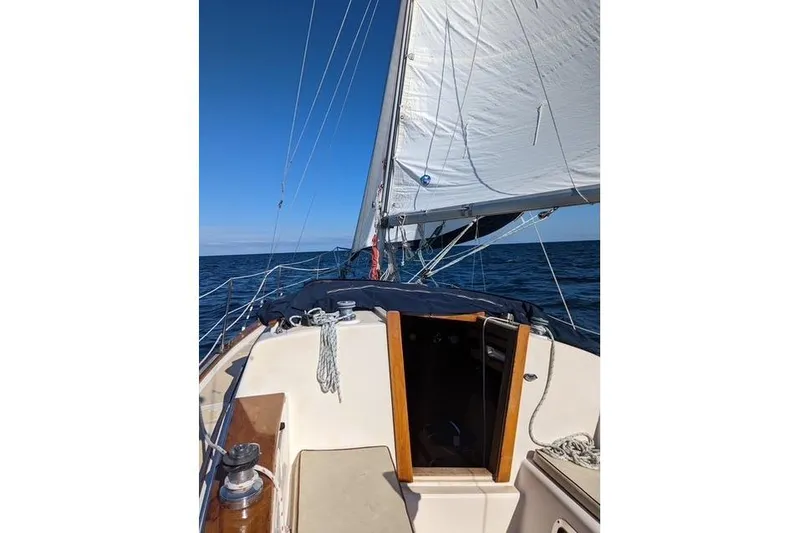 Slide: The Image of 1988 Island Packet 27 sailboat on open sea under clear blue sky. - 3