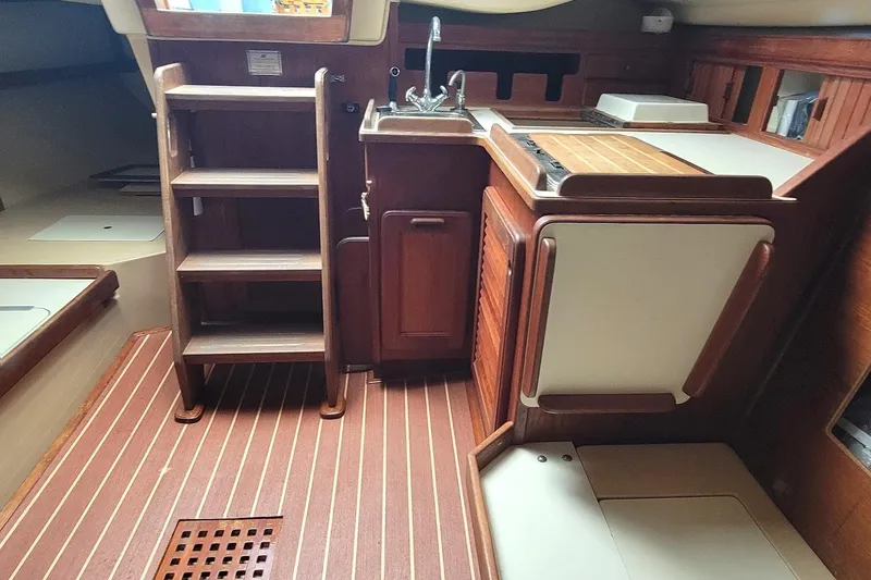 Slide: The Image of Interior of 1988 Island Packet 27 sailboat with wooden cabinetry and compact kitchen area. - 3