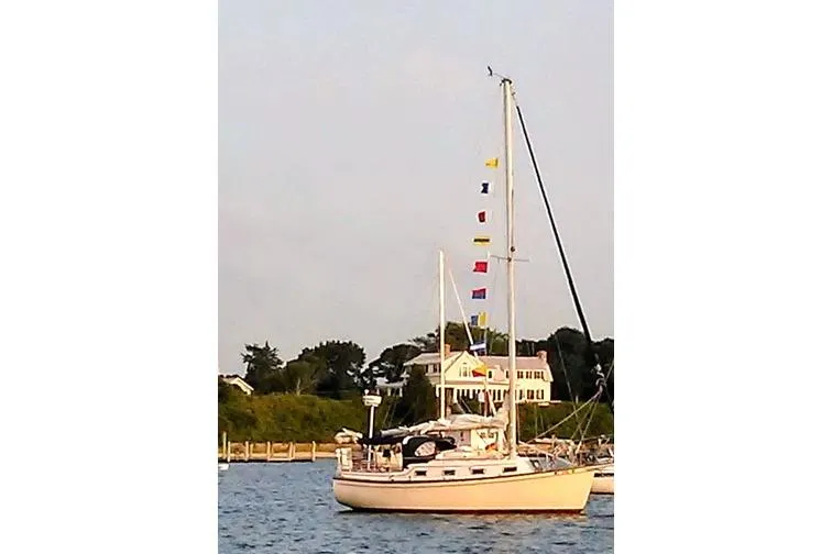 Slide: The Image of 1988 Island Packet 27 sailboat with colorful flags on a calm water backdrop. - 5