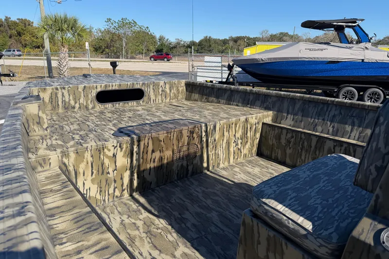 Slide: The Image of 2026 Smoker Craft Sportsman 1866 boat with camouflage interior, parked outdoors. - 11