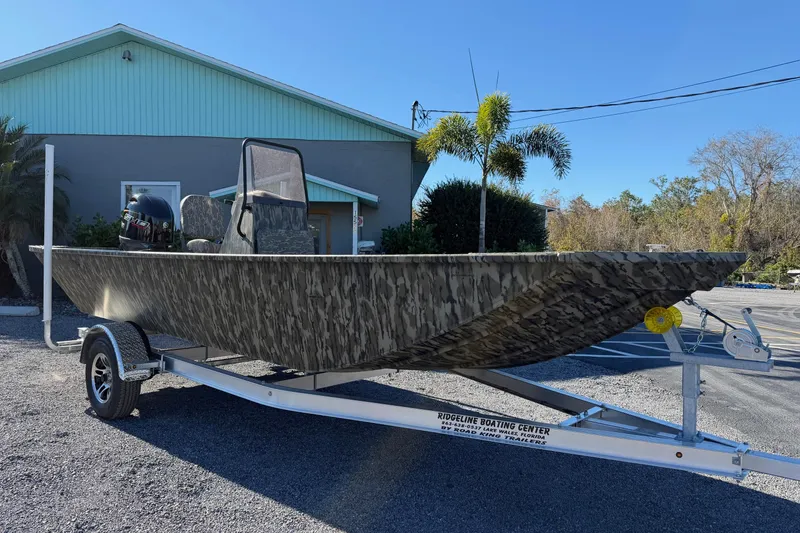 Slide: The Image of 2026 Smoker Craft Sportsman 1866 boat on trailer, camo design, parked outdoors. - 6