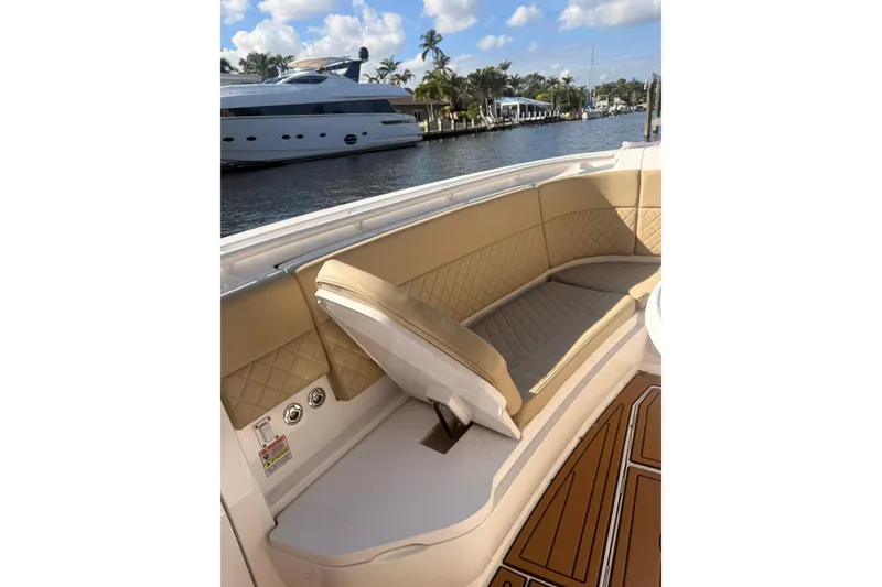 Slide: The Image of 2019 Intrepid 345 Nomad FE boat interior with tan seating and scenic waterfront view. - 10