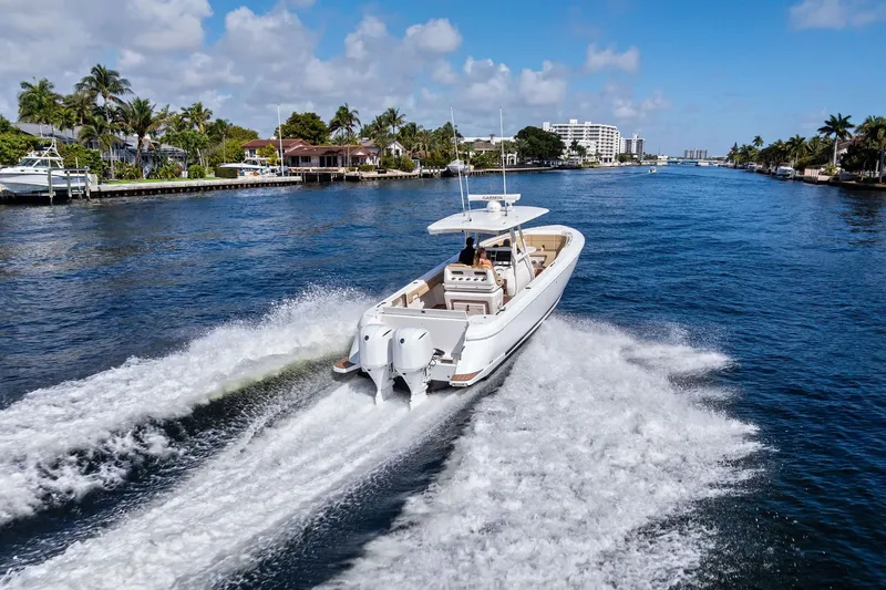 Slide: The Image of 2019 Intrepid 345 Nomad FE boat with blue seating, docked by waterfront. - 38