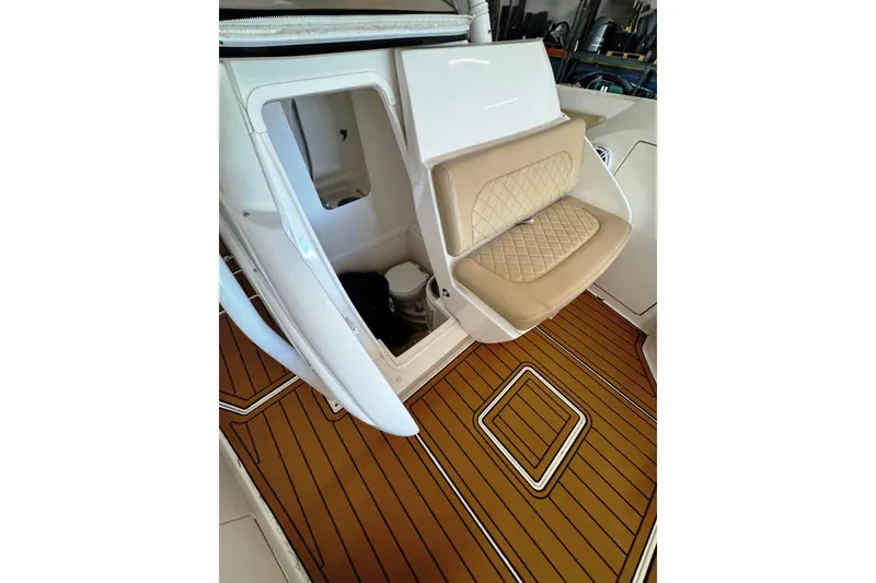 Slide: The Image of 2019 Intrepid 345 Nomad FE boat interior with cushioned seating and wooden flooring. - 8