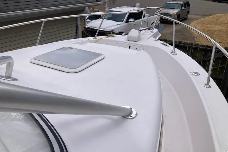 Slide: The Image of 2005 Pro-Line 30 Walkaround boat deck with railing and hatch, parked near vehicles. - 9