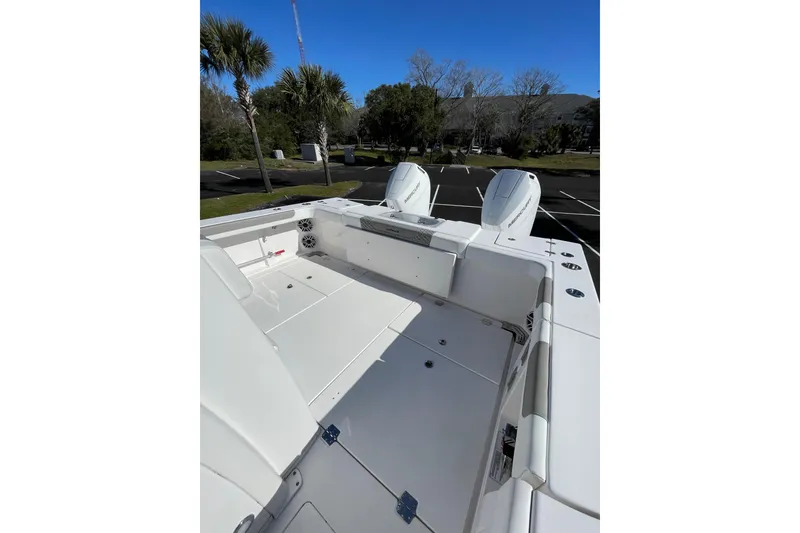Slide: The Image of 2024 Caymas 34 CT boat deck with dual engines, parked outdoors under clear blue sky. - 21