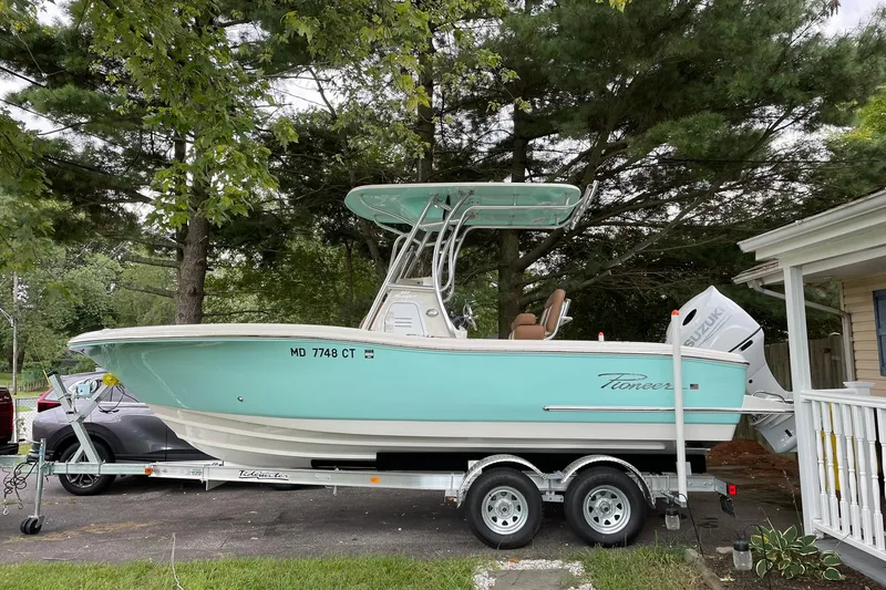 The Image of 2021 Pioneer 222 Sportfish boat on trailer, parked outdoors near trees and house. - 0