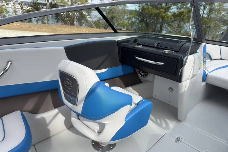 Slide: The Image of 2026 Crownline 220 SS boat interior with blue and white seating, sleek dashboard, and lake view. - 12