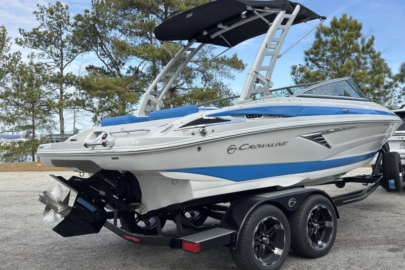 Slide: The Image of 2026 Crownline 220 SS boat on trailer, featuring sleek design and blue accents, parked outdoors. - 18