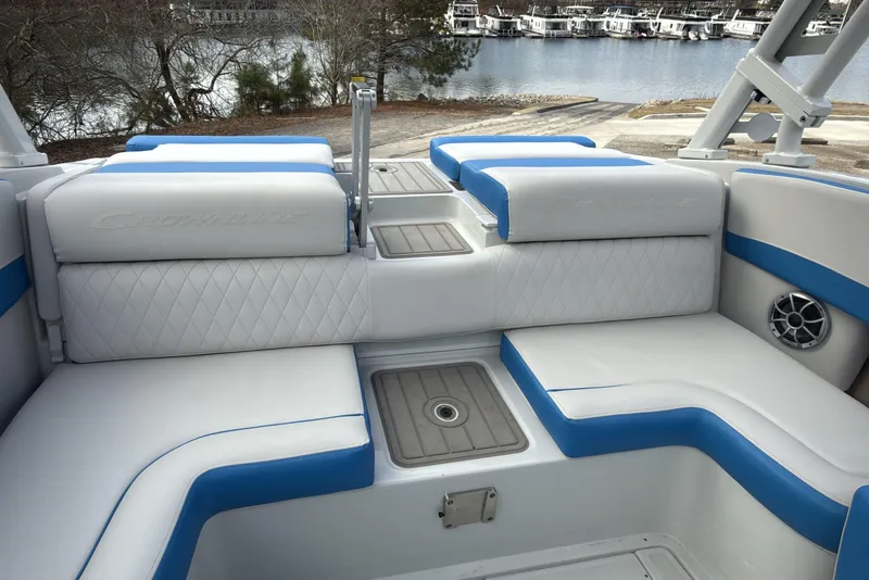 Slide: The Image of 2026 Crownline 220 SS boat interior with white and blue seating, docked by a lake. - 7
