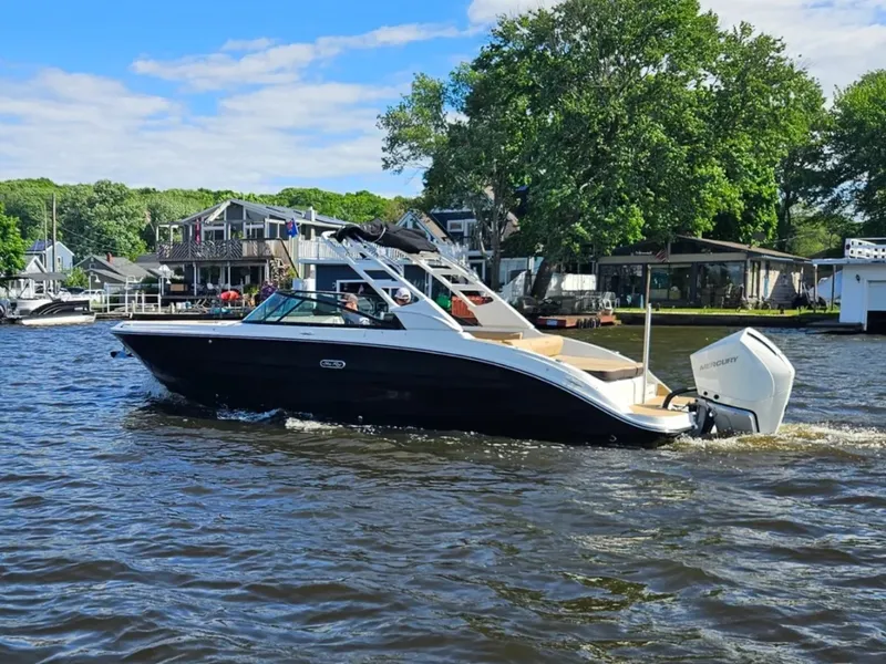 Slide: The Image of A 2026 Sea Ray SDX 270 Outboard cruising on a river. It features a sleek design and outboard engine. - 2