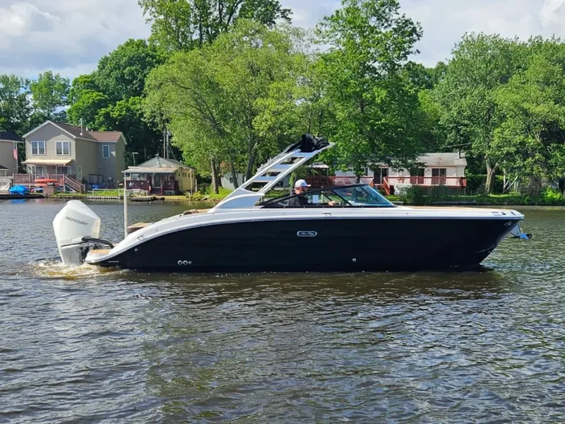 Slide: The Image of A 2026 Sea Ray SDX 270 Outboard cruising on a calm river, surrounded by trees and houses. - 3