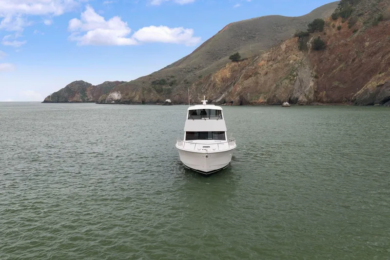 Slide: The Image of 2014 Maritimo M50 yacht on calm waters with scenic rocky coastline. - 6