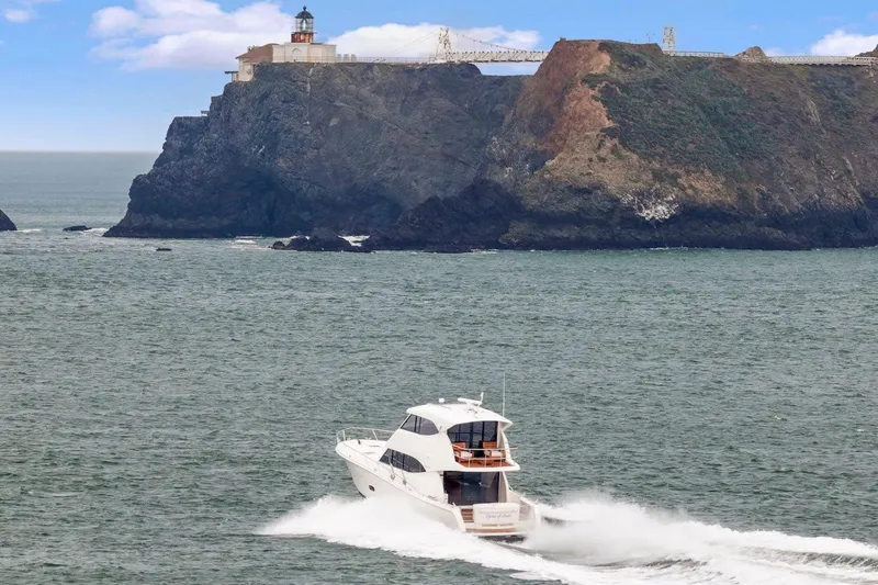 Slide: The Image of 2014 Maritimo M50 yacht cruising near rocky coastline with lighthouse. - 83