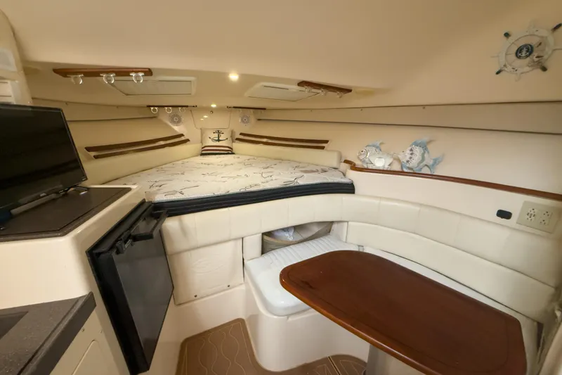Slide: The Image of 2006 Grady-White Express 330 cabin interior with bed, table, and TV. - 12