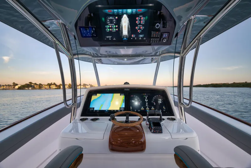 Slide: The Image of 2026 Mag Bay 43 CC boat helm with advanced navigation displays on calm water. - 10