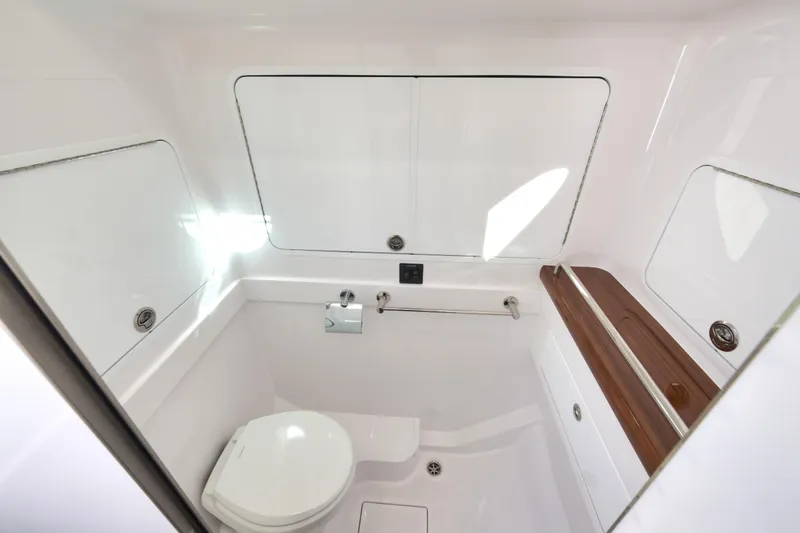 Slide: The Image of 2026 Mag Bay 43 CC boat bathroom with sleek white interior and wooden accents. - 16
