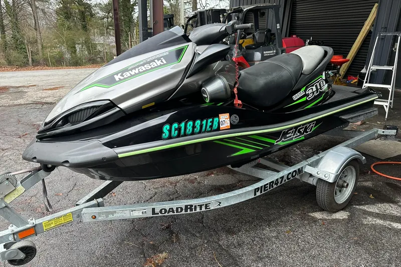 The Image of 2016 Kawasaki Jetski Ultra 310LX on trailer, black and green design. - 1