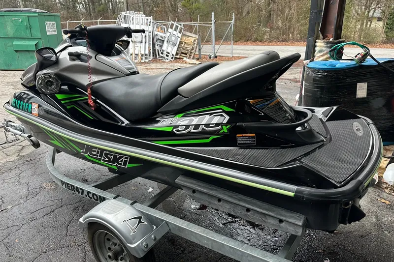 Slide: The Image of 2016 Kawasaki Jetski Ultra 310LX on trailer, black and green design, parked outdoors. - 2