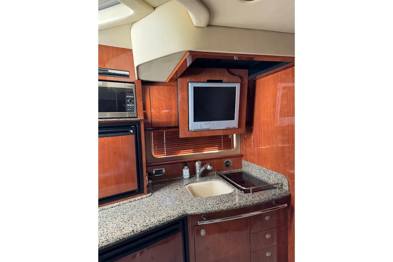 Slide: The Image of 2006 Sea Ray 38 Sundancer yacht interior with kitchenette, TV, and wooden cabinetry. - 19