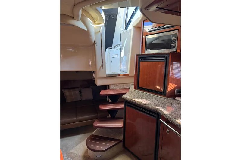 Slide: The Image of 2006 Sea Ray 38 Sundancer interior with wooden cabinetry, microwave, and stairs. - 25