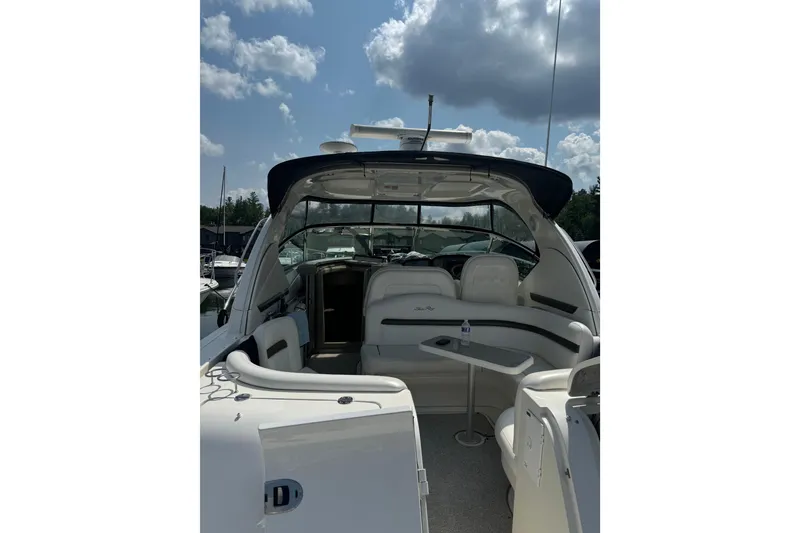 Slide: The Image of 2006 Sea Ray 38 Sundancer yacht interior with seating and table under a cloudy sky. - 7