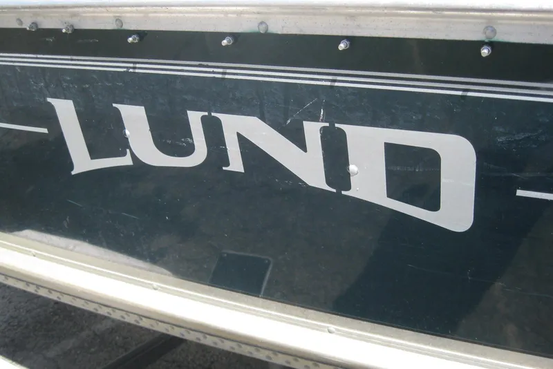 Slide: The Image of 1999 Lund 1440-V Rebel Tiller boat with visible logo on the side. - 3